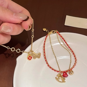 Close-up of gold plated horse bracelet with red beads and luxury zircon details
