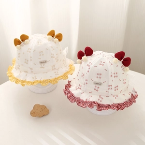 Détail de chapeaux bébé avec imprimés cerises, volants à carreaux et nœuds décoratifs