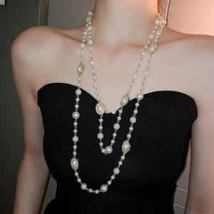 Detail of elegant double-layer pearl necklace with gold-rimmed accents on black top
