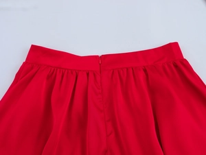 Détail d'une jupe en satin rouge avec fermeture éclair invisible et plis à la taille