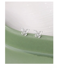 Close-up of S925 sterling silver butterfly stud earrings on ceramic dish edge