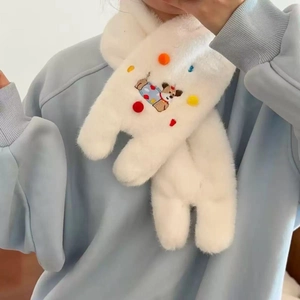 Detail of white plush scarf with colorful pom-poms and cartoon dog embroidery