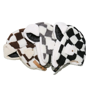 Close-up of checkerboard plush trapper hats in brown, grey, and black with ear flaps