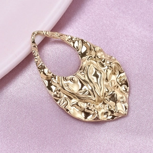 Detail of gold hammered teardrop pendant on purple satin fabric for DIY jewelry making