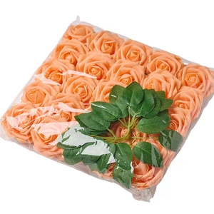 Detailed view of artificial orange rose flower heads with green leaves in packaging