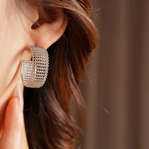 Primo piano di una modella con eleganti orecchini a cerchio a rete d'argento a forma di C