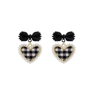 Close-up of bow knot earrings with heart shaped pearl border and black white plaid fabric