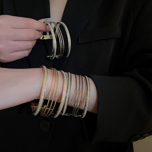 Detail of layered metal open bracelets with glitter finish and matte texture on wrist