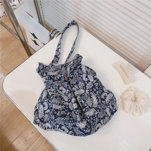 Detail view of a navy blue paisley canvas tote bag on a white surface with accessories