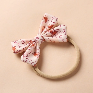 Detail of floral bow headband with orange blossoms and stretchy nylon elastic band