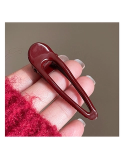 Detail view of a burgundy geometric pleated hair clip with glossy painted finish