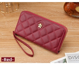 Quilted dark red wristlet wallet featuring a golden floral clasp on a wooden surface