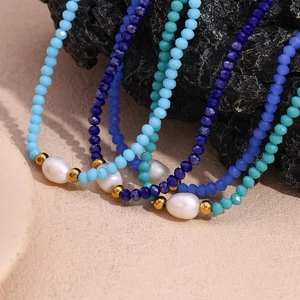 Detail of beaded necklace with blue crystal beads, white pearl and golden accents