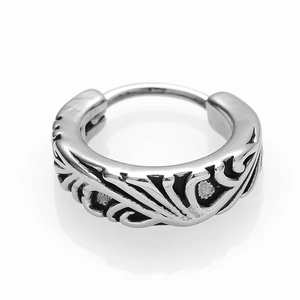 Detail of vintage silver hoop earring with embossed tribal patterns and black oxidation