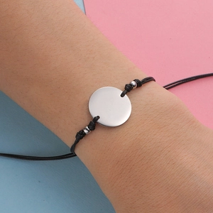 Detail of adjustable black waxed cord bracelet with a polished silver round charm