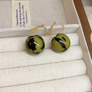 Detail of vintage gold hook earrings with olive green marble texture sphere drops