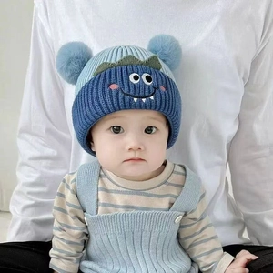 Cute baby winter knit hat with cartoon monster design and light blue plush pom-poms