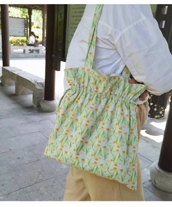 Detalle de bolso tote de lona con estampado floral amarillo y cierre de cordón al hombro