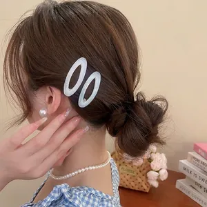 Elegant white acetate oval hair clips and pearl jewelry worn by a model in soft lighting