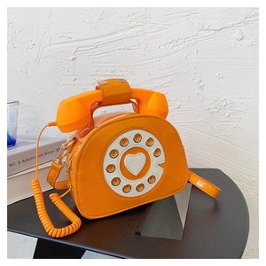Detail of creative orange retro telephone handbag with rotary dial and handset handle