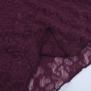 Detailed close-up of dark purple floral lace fabric with intricate hollow mesh pattern