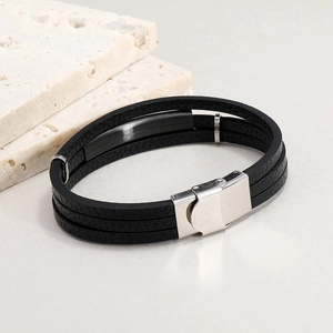 Detail of multi-layer black leather bracelet with silver clasp on stone surface