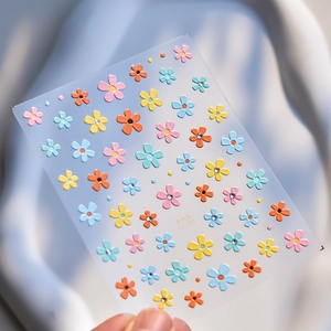 Macro detail of 3D 5-petal flower nail stickers with colorful rhinestones on transparent base
