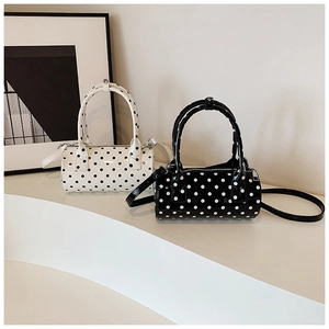 Close-up of polished polka dot boston bags in black and white with metal zipper detail