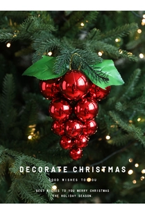 Red shiny grape bunch Christmas ornament hanging on a festive tree with warm lights