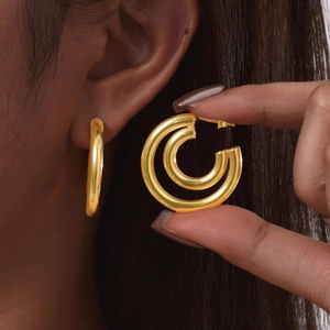 Detailed view of polished golden double hoop earrings on model for modern fashion look