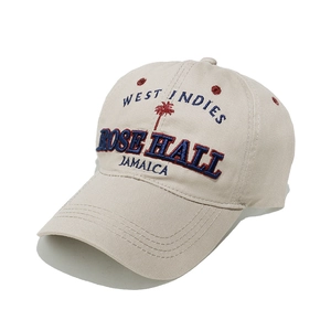 Close-up of West Indies and palm tree embroidery on a beige cotton baseball cap