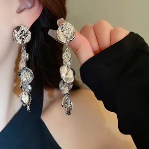 Boucles d'oreilles pendantes argentées irrégulières à effet martelé portées par un mannequin
