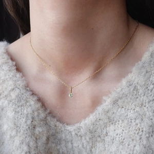 Primo piano della collana in acciaio al titanio dorato con pietra portafortuna e zircone