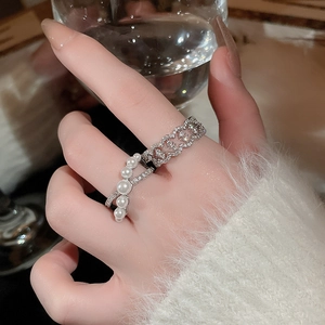 Detailed close-up of a silver pearl and zircon crossover ring set on a model's hand