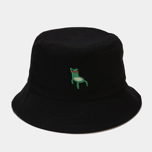 Close-up of cute green frog embroidery on a black cotton canvas bucket hat surface