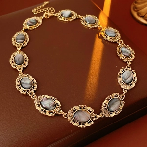 Detail of vintage gold necklace with grey resin stones in ornate filigree settings