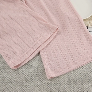 Detail of pink knitted pajama pants featuring hollow-out jacquard patterns and fine stitching