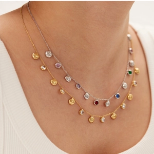 Detail of layered stainless steel necklaces with shell pendants and colorful zircon stones
