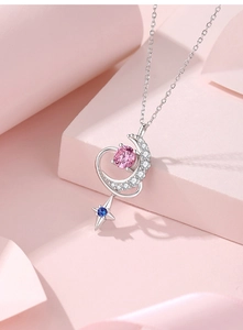 Close-up of S925 silver moon and star pendant with pink and blue stones on silk