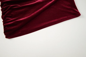 Detailed macro view of the wine red velvet fabric texture and stitching on the dress hem