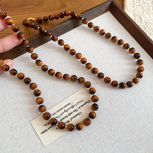 Macro shot of tiger eye beaded necklace with gold and silver spacers on wooden tray
