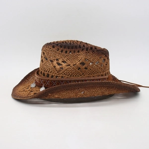 Detail view of woven brown straw cowboy hat with ethnic embroidery and silver pendants