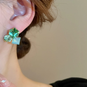 Détail de boucles d'oreilles vintage avec cristaux géométriques verts et bleus
