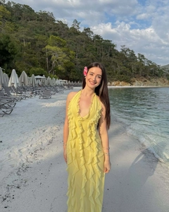 Close-up of yellow halter neck long dress with ruffles on a sunny tropical beach
