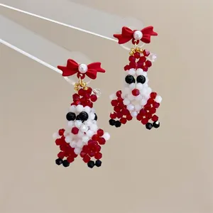 Detail of handmade beaded Santa Claus earrings with a red matte bow and faux pearl accent