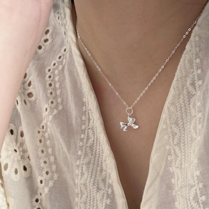 Detailed close-up of a 925 sterling silver bow pendant on a delicate chain necklace