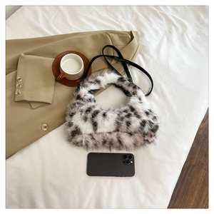 Macro detail of plush faux fur crescent bag with black leather strap and cow print texture