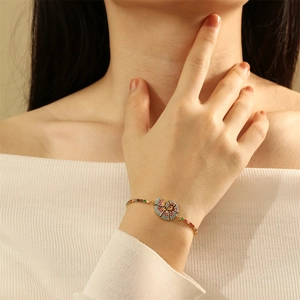 Close-up of model wearing a gold shell bracelet with multi-color zircon stones