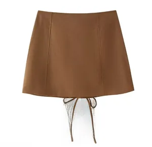 Detail of brown high-waist A-line skirt with decorative bow knot and matte texture