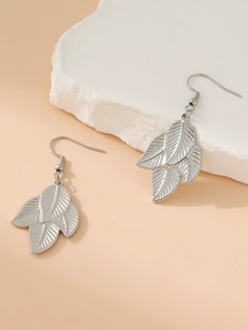 Detail shot of silver leaf-shaped earrings with intricate vein textures on a white stone